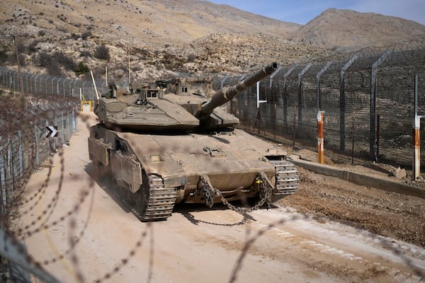 An Israeli tank maneuvers next to the security fence near the so-called Alpha Line that separates the Israeli-annexed Golan Heights from Syria, in the town of Majdal Shams, Wednesday, Dec. 11, 2024. (AP Photo/Matias Delacroix)