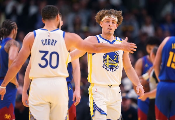 Golden State Warriors guard Stephen Curry, left, congratulates guard Brandin Podziemski after he made a basket and drew a foul shot against the Denver Nuggets in the first half of an Emirates NBA Cup basketball game Tuesday, Dec. 3, 2024, in Denver. (AP Photo/David Zalubowski)