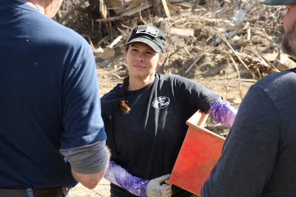 Jill Holtz listens intently as Michael Davidson, a local business owner, tells her and David Wiley, a storm recovery volunteer, about Hurricane Helene's damage in Swannanoa, N.C., on Thursday, Feb. 6, 2025. (AP Photo/Makiya Seminera)