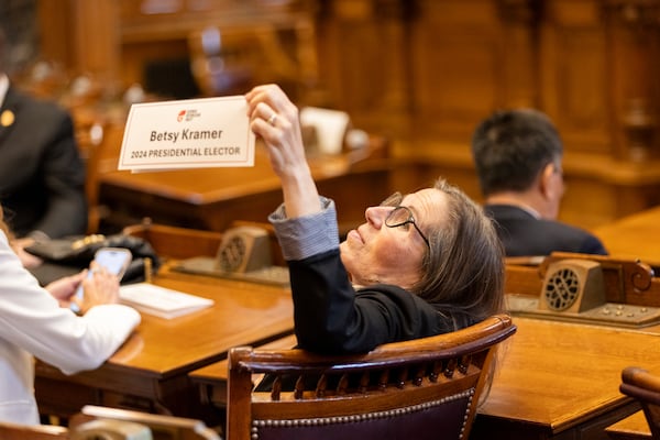 Georgia Republican elector Betsy Kramer shows her name placard to people in the gallery, as electors gather to formally cast their votes for Donald Trump and JD Vance in the Senate chambers at the state Capitol in Atlanta, Tuesday, Dec. 17, 2024. (Arvin Temkar/Atlanta Journal-Constitution via AP)