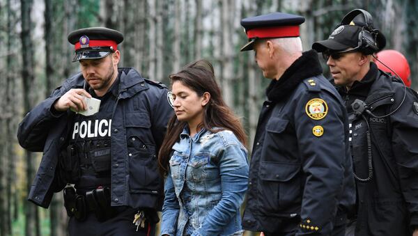 Police escort a woman who was rescued from a downtown Toronto crane early Wednesday, April 26, 2017. Some streets in the downtown core were closed as dozens of construction workers and commuters gazed skyward to watch police and firefighters try to rescue the woman who got stuck atop a tall construction crane. (Frank Gunn/The Canadian Press via AP)