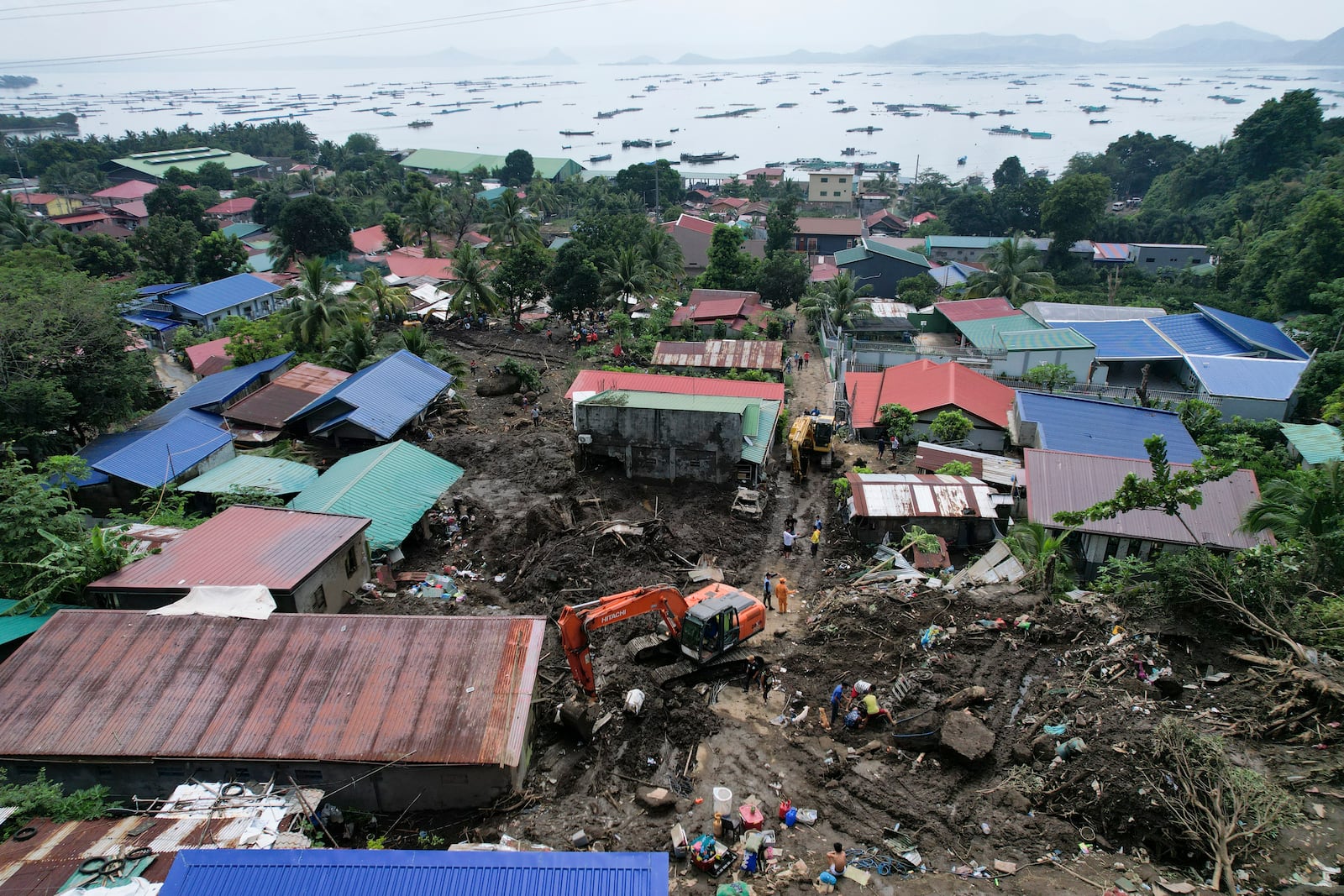 Rescuers use backhoe as they search for bodies under the rubble after a landslide triggered by Tropical Storm Trami struck homes, leaving several villagers dead in Talisay, Batangas province, Philippines Saturday, Oct. 26, 2024. (AP Photo/Aaron Favila)