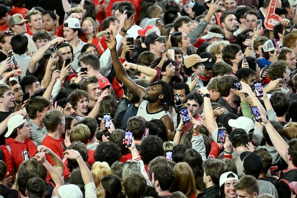 Georgia basketball players and fans celebrate on the Stegeman Coliseum court. 