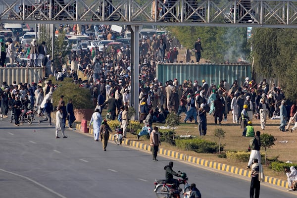 Supporters of imprisoned former premier Imran Khan's Pakistan Tehreek-e-Insaf party, gather to remove shipping container to clear way for their rally demanding Khan's release, in Islamabad, Pakistan, Tuesday, Nov. 26, 2024. (AP Photo/Anjum Naveed)