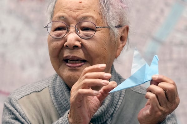 Shizuyo Takeuchi, 94-year-old Tokyo raid survivor, holds a paper dove as she shares her experience in front of a map of the areas damaged during the 1945 Tokyo Firebombing at the Center of the Tokyo Raids and War Damage on Feb. 24, 2025, in Tokyo. (AP Photo/Eugene Hoshiko)