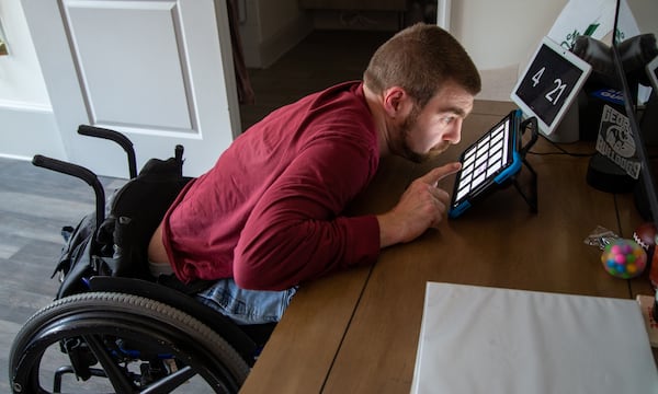 Matt Thompson work with his computer table assistant in his room at Champions Place. PHIL SKINNER FOR THE ATLANTA JOURNAL-CONSTITUTION.