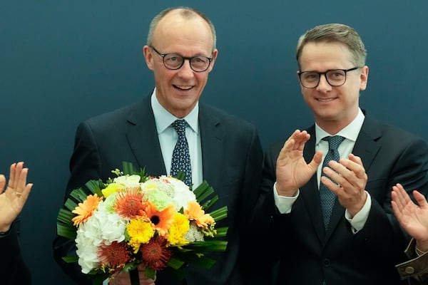 Friedrich Merz, left, leader of the Christian Democratic Union (CDU), stand next to Secretary General Carsten Linnemann, right, after he receives flowers at the CDU's headquarters, in Berlin, Germany, Monday, Feb. 24, 2025. (AP Photo/Martin Meissner)