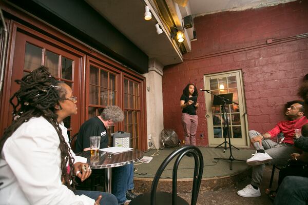 Java Monkey in Decatur hosts a weekly poetry open mic (sometimes slam). The poets sign up at 7:30 p.m. every Sunday and the event begins at 8:00 p.m. This high-energy poetry event is hosted by Kodac Harrison who is wearing a black Java Monkey Slam t-shirt and glasses.