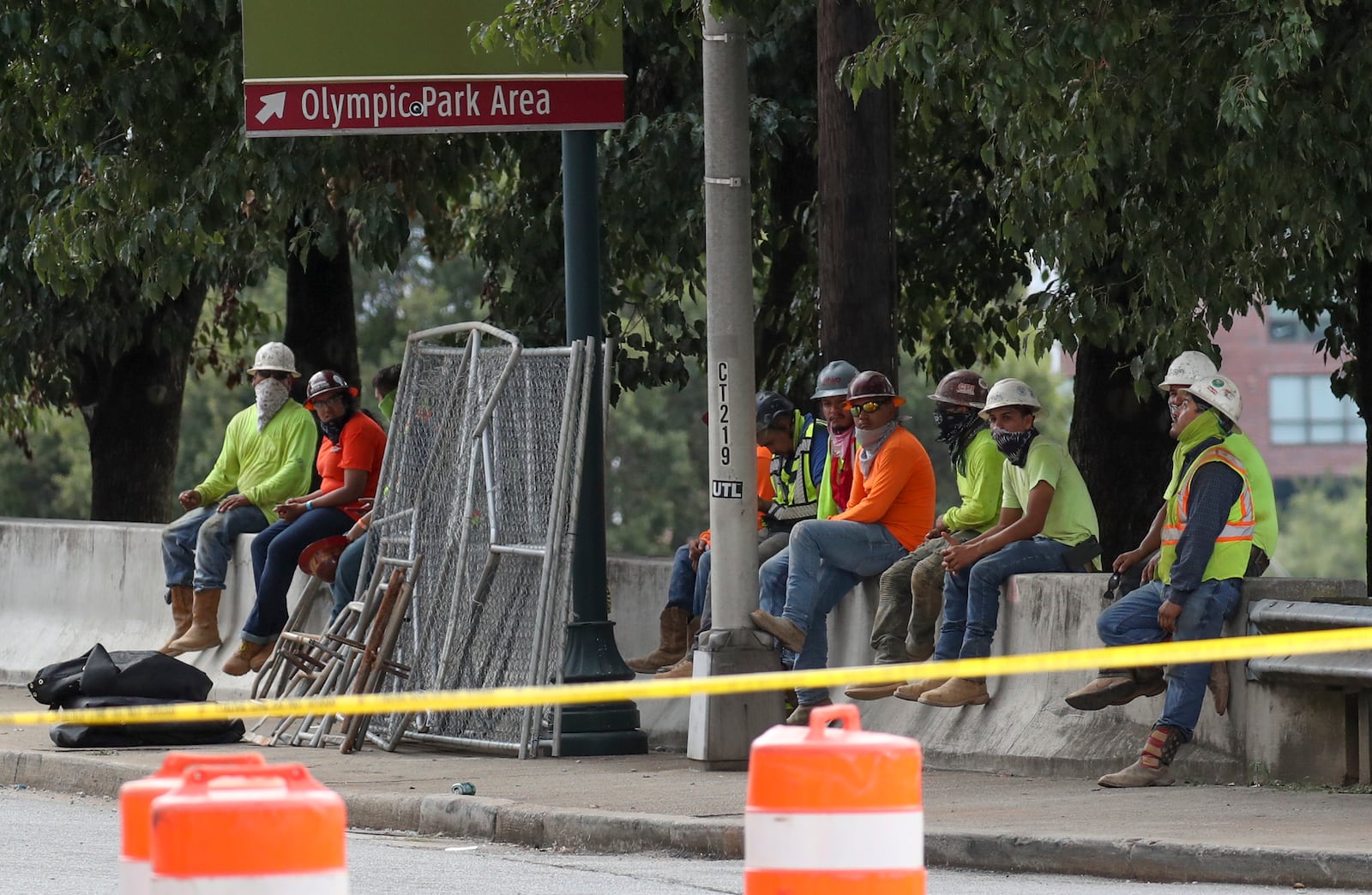 Workers wait across from the scene where the parking deck collapsed Friday.