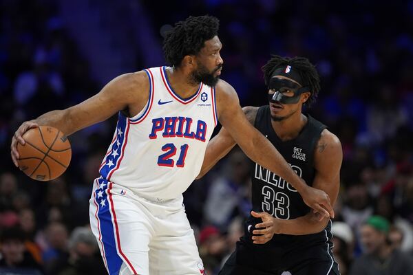 Philadelphia 76ers' Joel Embiid, left, tries to get past Brooklyn Nets' Nic Claxton during the first half of an NBA basketball game, Saturday, Feb. 22, 2025, in Philadelphia. (AP Photo/Matt Slocum)