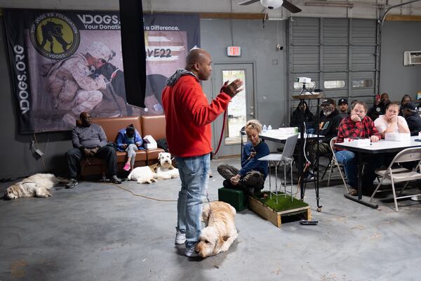 Antonio Merriweather, with his service dog Marley, talks to veterans who applied for the VDOGS program that pairs service dogs with veterans during an orientation session at Top Dogg K9 Foundation in Lilburn on Saturday, Feb. 15, 2025. Ben Gray for the Atlanta Journal-Constitution