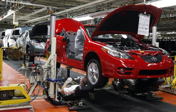 FILE - In this Nov. 10, 2008, file photo, members of a production team work on the under carriage of a Toyota Solara convertible on the assembly line at the Toyota Motor Manufacturing Kentucky plant in Georgetown, Ky. President Donald Trump’s relentless push for more manufacturing jobs has forced the auto industry into a delicate dance of contradictions. Toyota did the waltz with its long-planned announcement Monday, April 10, 2017, that it would spend $1.33 billion to retool the Kentucky factory. (AP Photo/James Crisp, File)