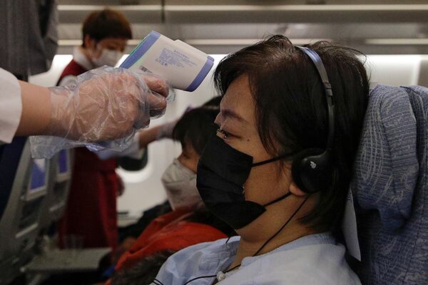 Flight attendants take temperatures of passengers as a preventive measure for the coronavirus on an Air China flight from Melbourne to Beijing.