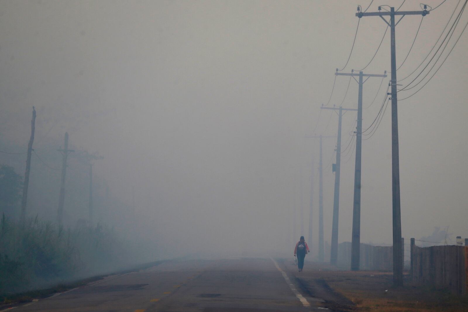 FILE - A person walks on the BR-319 highway through smoke from a forest fire that reaches Careiro Castanho in Brazil's Amazonas state, Sept. 6, 2023. (AP Photo/Edmar Barros, File)