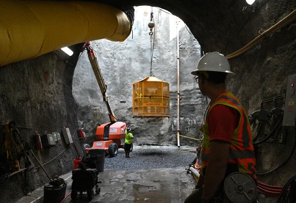 June 9, 2022 Atlanta - A gigantic crane lifts a cage to transport crew between the ground and the tunnel under construction beneath Hartsfield-Jackson International on Thursday, June 9, 2022. Sixty feet below the busiest airport, crews from the Clark Construction-led joint venture of Clark/Atkinson/Technique have been excavating a 833-foot extension for the Plane Train tunnel.  (Hyosub Shin / Hyosub.Shin@ajc.com)