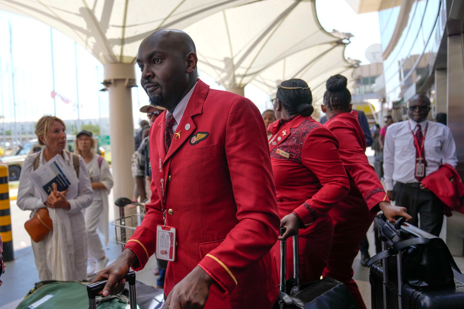 Kenya airways flight attendants queue alongside stranded passengers waiting for their delayed flights out of JKIA airport after flights were grounded following workers’ protesting a planned deal between the government and a foreign investor, in Nairobi, Kenya, Wednesday, Sept. 11, 2024. (AP Photo/Brian Inganga)