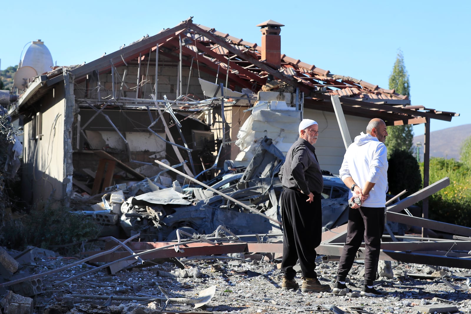 Druze men observe the site where an Israeli airstrike hit a compound housing journalists, killing three media staffers from two different news agencies according to Lebanon's state-run National News Agency, in Hasbaya village, southeast Lebanon, Friday, Oct. 25, 2024. (AP Photo/Mohammed Zaatari)