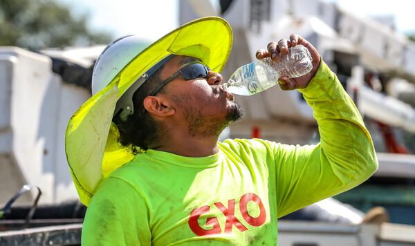 Fernando Rosales with RJH electrical contractors worked on installing an electrical box on Northside Drive near I-75 gets hydrated during the oppressive heat in metro Atlanta on Monday, Aug. 14, 2023. (John Spink / John.Spink@ajc.com)

