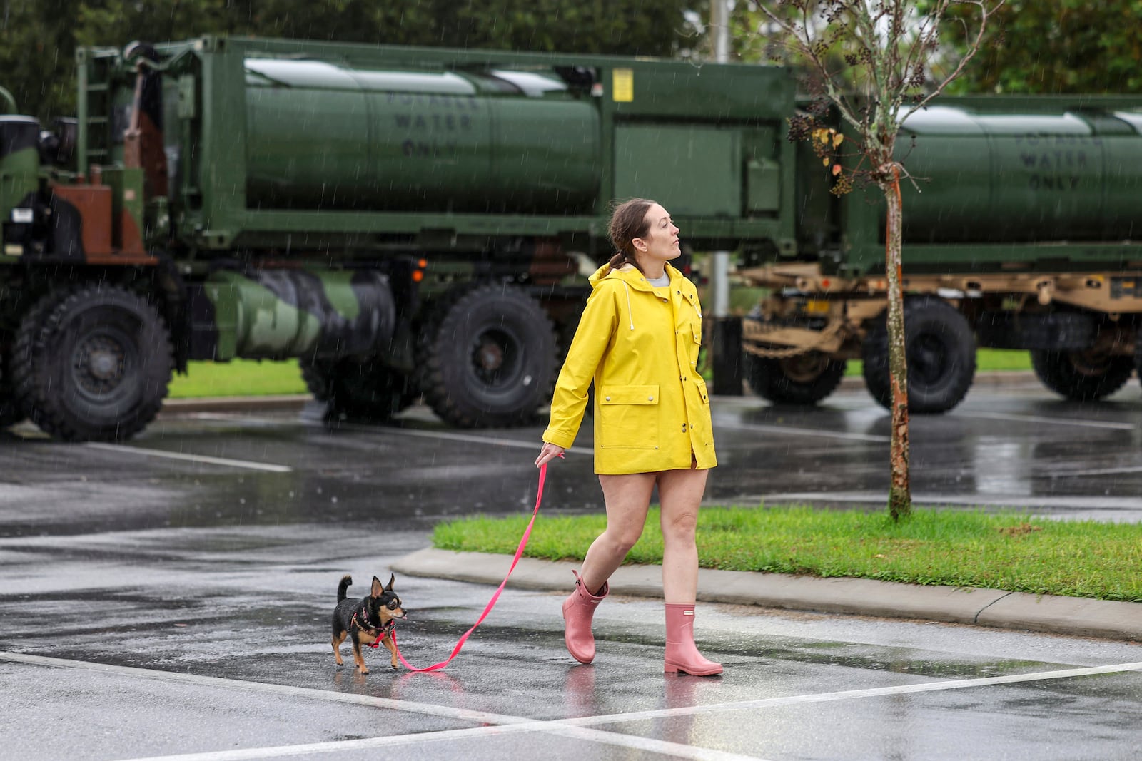 Erin Ferguson walks her dog while looking at equipment stationed by the Florida National Guard in preparation for Hurricane Milton, Wednesday, Oct. 9, 2024, in New Port Richey, Fla. (AP Photo/Mike Carlson)