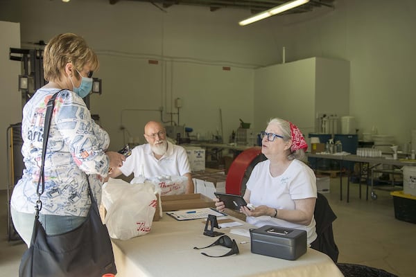 Betsey Dahlberg (right) and Paul (center) Allen, owners of Hope Springs Distillery, with Darlene Stokan (left), who purchased four bottles of their hand sanitizer, produced at their distillery in downtown Lilburn. (ALYSSA POINTER / ALYSSA.POINTER@AJC.COM)