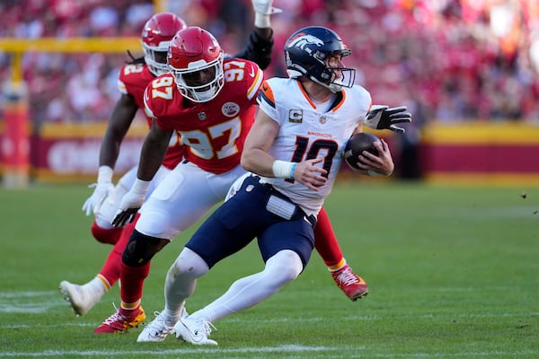 Denver Broncos quarterback Bo Nix (10) scrambles away from Kansas City Chiefs defensive end Felix Anudike-Uzomah (97) during the second half of an NFL football game Sunday, Nov. 10, 2024, in Kansas City, Mo. (AP Photo/Ed Zurga)