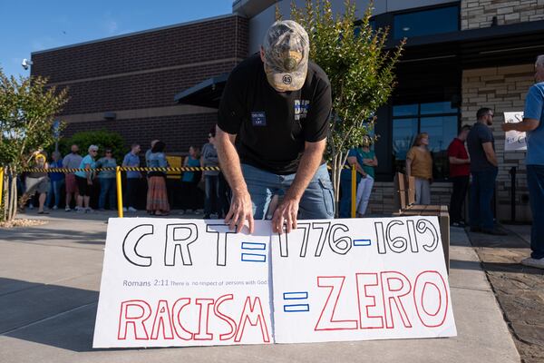 Rick Cox, who has a son in the Cherokee County school system, holds signs outside the school board chambers in Canton before a packed-to-capacity meeting on May 20, 2021. (Credit: Ben Gray for the Atlanta Journal-Constitution)