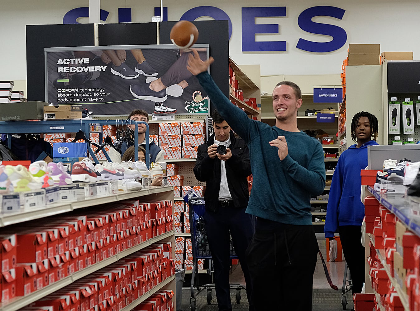 UGA quarterback Carson Beck tosses a football to a Boys and Girls club member in the shoe aisle. Carson Beck was on site at an Athens Academy store Sunday December 17, 2023, to give out gift cards to lucky members of area Boys and Girls Clubs. Academy contributed $200 for each child and he kicked in $135 more of his own money to help families out. 
credit: Nell Carroll for the AJC