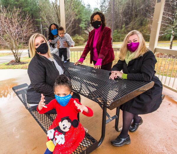 Blackwell film studio has traded land with DeKalb County making way for a new park with a splash pad, security, playgrounds and outdoor space for the Bouldercrest community.  Neighborhood leaders, including Sarah Cotten, from left, the Clark family (Demi, 3, front; mother Alison, 7-month-old Lucas), Pat Culp and Ingrid Buxbaum sit in an old gazebo that will soon be part of the film studio Friday, Feb 12, 2021. A mile away, ground has been broken for the new DeKalb park.   (Jenni Girtman for The Atlanta Journal-Constitution)