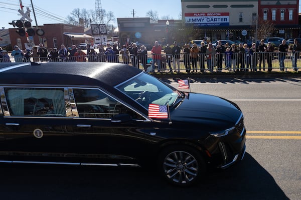 The hearse for former President Jimmy Carter passes through Plains in a motorcade on Saturday, January 4, 2025, following his death earlier this week. The procession will then head to Atlanta where Carter will lie repose at the Carter Center. (Arvin Temkar / AJC)