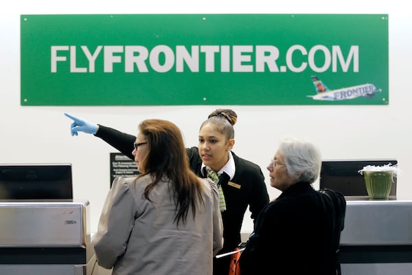 FILE - In this Oct. 15, 2014 file photo, a Frontier Airlines employee directs passengers at Cleveland Hopkins International Airport in Cleveland. There are few businesses that consumers love to hate more than airlines, but travelers seem to reserve a special level of vitriol for the no-frills, discount airlines. (AP Photo/Tony Dejak, File)