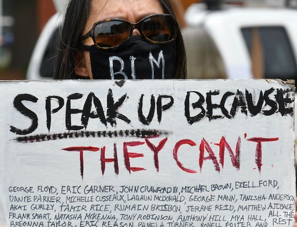 A protester holds a sign Saturday at a rally in Forsyth County. (Photo: Hyosub Shin/AJC)