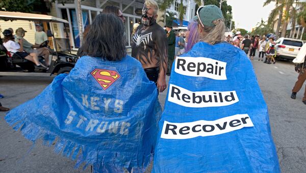 In this Friday, Oct. 27, 2017, photo provided by the Florida Keys News Bureau, residents of the Lower Florida Keys use portions of blue tarps as costumes as they walk down Fleming Street during the Masquerade March in Key West, Fla.   The event was staged almost seven weeks after Hurricane Irma passed through the Keys on Sept. 10. Key Largo and Key West were least impacted by the storm. (Andy Newman/Florida Keys News Bureau via AP)