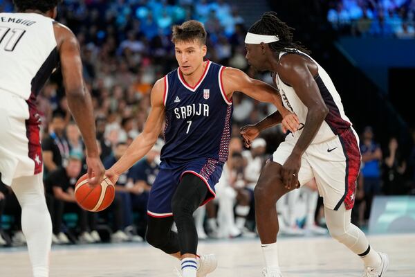 Bogdan Bogdanovic (7), of Serbia drives past United States' Jrue Holiday (12) during a men's semifinals basketball game at Bercy Arena at the 2024 Summer Olympics, Thursday, Aug. 8, 2024, in Paris, France. (AP Photo/Michael Conroy)