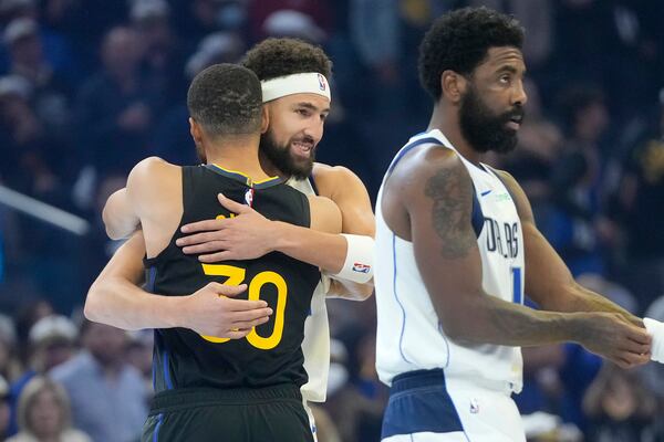 Golden State Warriors guard Stephen Curry, left, hugs Dallas Mavericks guard Klay Thompson, middle, as guard Kyrie Irving, right, walks on the court before an Emirates NBA Cup basketball game in San Francisco, Tuesday, Nov. 12, 2024. (AP Photo/Jeff Chiu)