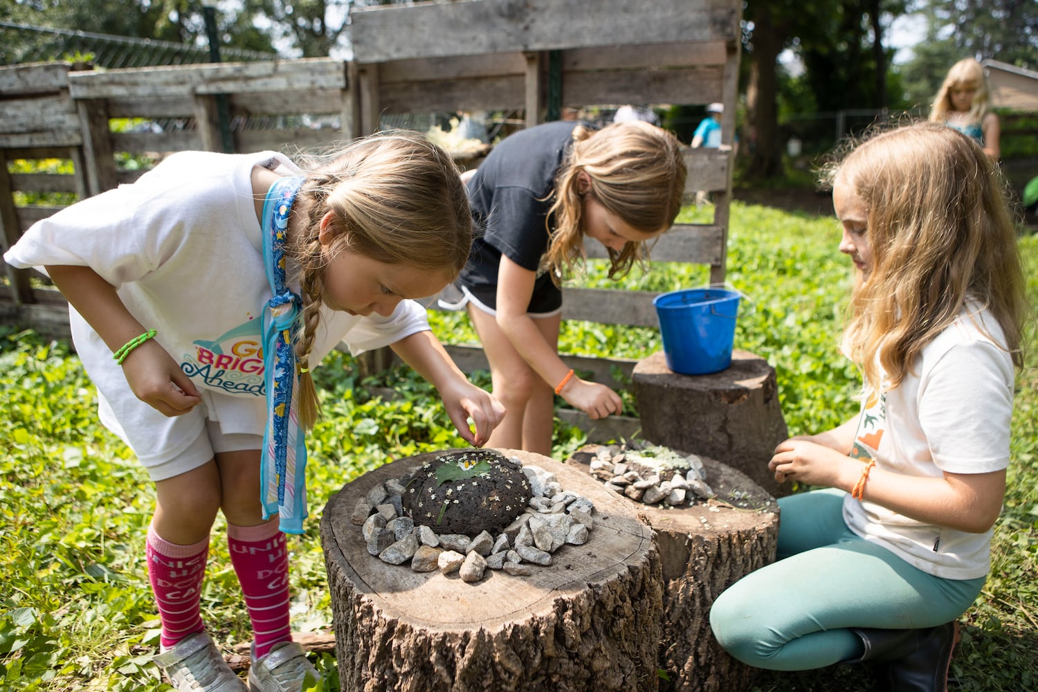 Caroline Gurley (left), Lotte Matichak (center) and Martha Underwood (right) make mud pies during summer camp at Our Giving Garden on Wednesday, June 7, 2023, in Mableton, Georgia. Our Giving Garden is a nonprofit community garden that donates fresh produce to families without access to it. CHRISTINA MATACOTTA FOR THE ATLANTA JOURNAL-CONSTITUTION.