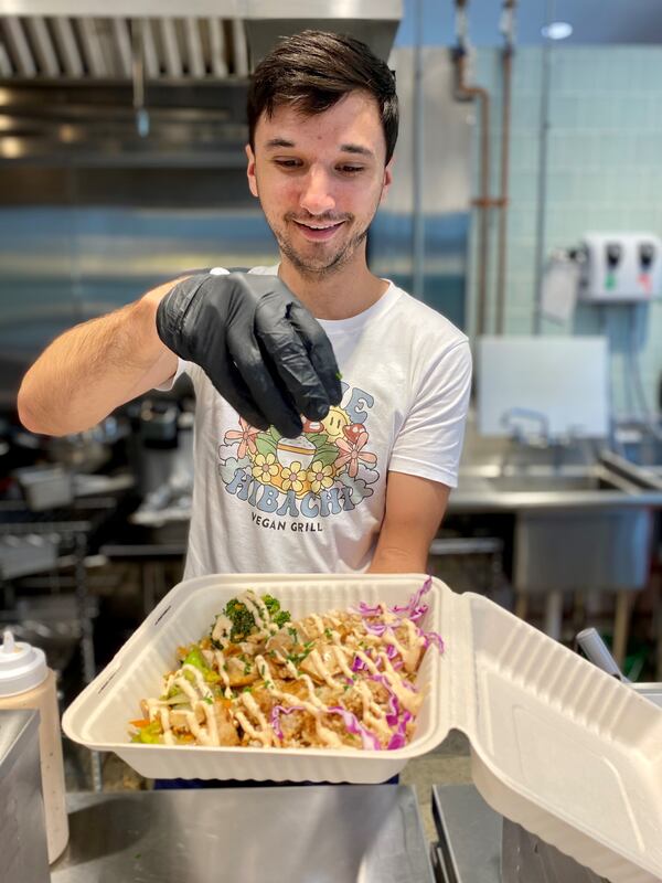 Josh Brock, owner of Hippie Hibachi Vegan Grill, garnishes a meal for a waiting customer. Wendell Brock for The Atlanta Journal-Constitution