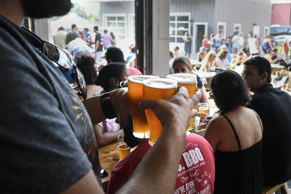 A patron carries out three beers for him and friends at Gate City Brewing, which has plenty of Roswell dining destinations nearby. CONTRIBUTED BY JOHN AMIS