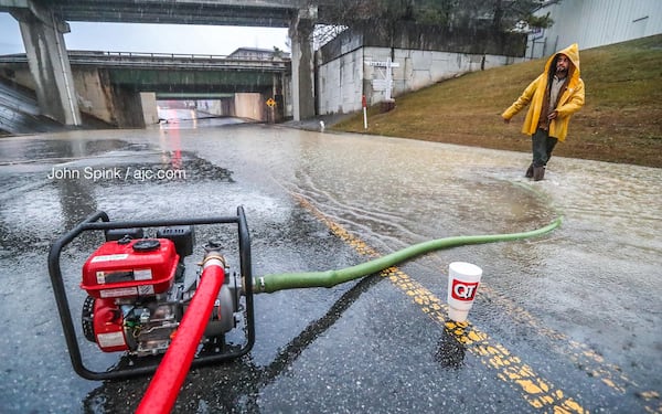 Michael Navarro adjusts a pump on Chamblee Dunwoody Road, which is flooded. The road is closed between American Industrial Way and New Peachtree Road