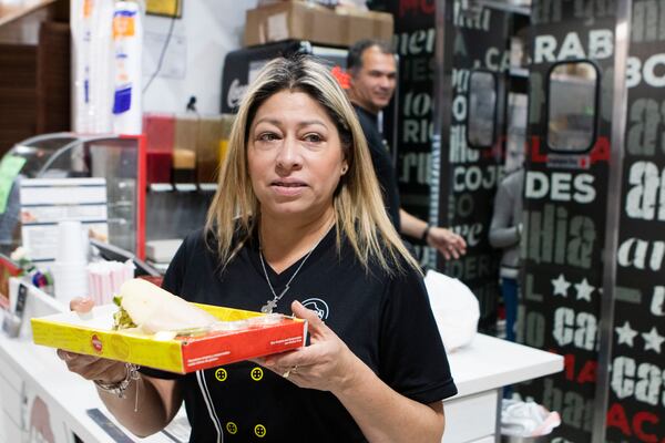 Claudia Jimenez, owner of Arepa Grill, serves food to customers in her restaurant at Plaza Fiesta. CHRISTINA MATACOTTA FOR THE ATLANTA JOURNAL-CONSTITUTION.