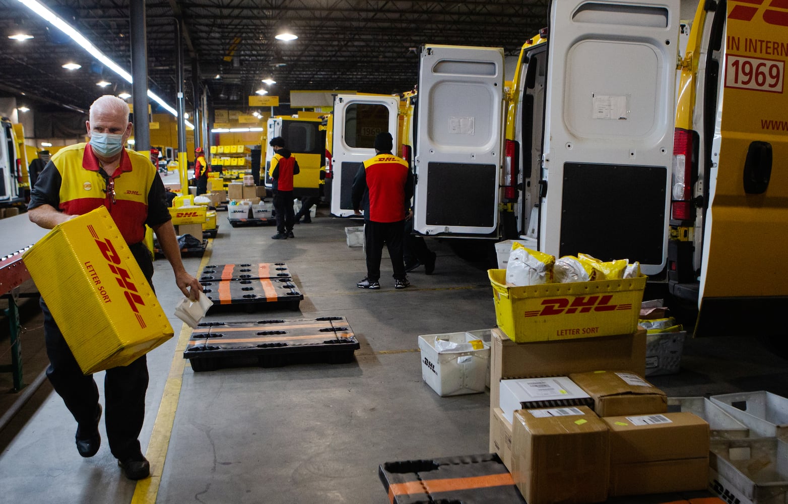 Tim Brothers (left) carries a box across the DHL Express shipping center on Wednesday, December 16, 2020, in Atlanta. Workers at the shipping center worked to fulfill orders during the holiday rush. CHRISTINA MATACOTTA FOR THE ATLANTA JOURNAL-CONSTITUTION.