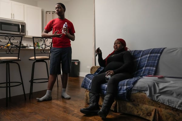 Zuleika, right, and her son Josafat, 14, immigrants from Central America seeking asylum, look at a TV together at their home Thursday, Feb. 20, 2025, in Chicago. (AP Photo/Erin Hooley)