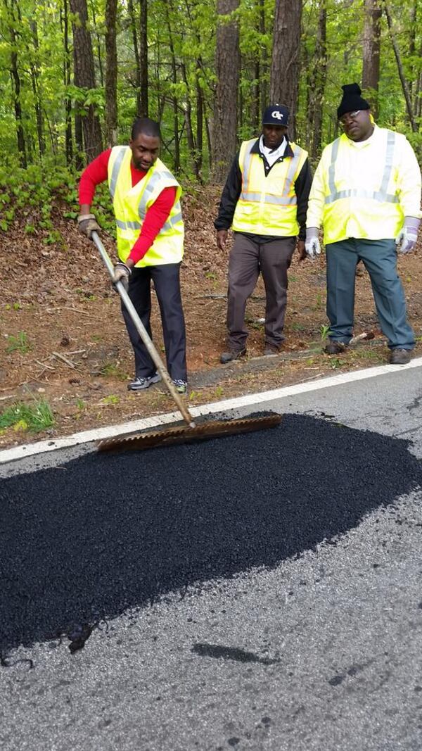 Former DeKalb County CEO Lee May helped spread asphalt over a pothole on Kensington Road.