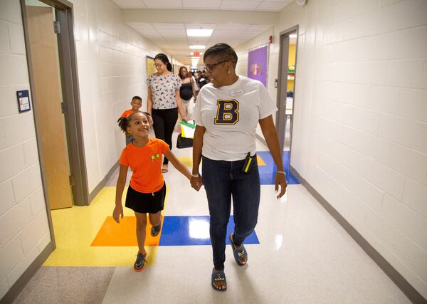 Beecher Hills Elementary school principal Crystal Jones (R) walks down the hall while holding the hand of Olivia Sorel during the first open house after the schools’ extensive renovation Friday, August 9, 2019.STEVE SCHAEFER / SPECIAL TO THE AJC