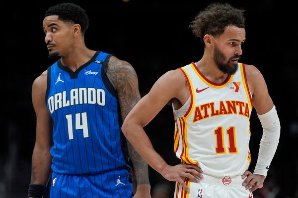 Atlanta Hawks guard Trae Young (11) raects to play in the closing seconds of the second half of an NBA basketball game as Orlando Magic guard Gary Harris (14) looks on, Thursday, Feb. 20, 2025, in Atlanta. (AP Photo/Mike Stewart)