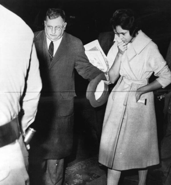 Charlayne Hunter is escorted from the Univeristy of Georgia campus as a safety precaution, as students violently protest against integration on Jan. 12, 1961. Dean Tate (L) assists her to a highway patrol car for the drive back to Atlanta. (Bill Young / AJC Archive at GSU Library AJCP551-061i)