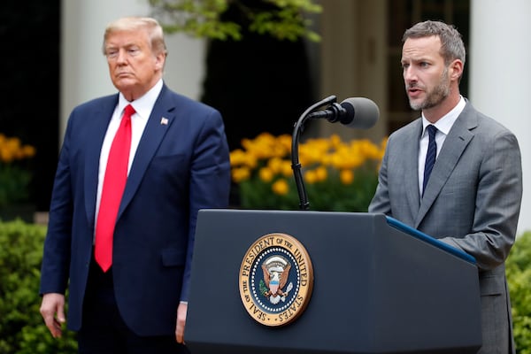 FILE - President Donald Trump listens as Adam Boehler, CEO of U.S. International Development Finance Corporation, speaks about the coronavirus in the Rose Garden of the White House, Tuesday, April 14, 2020, in Washington. (AP Photo/Alex Brandon, File)