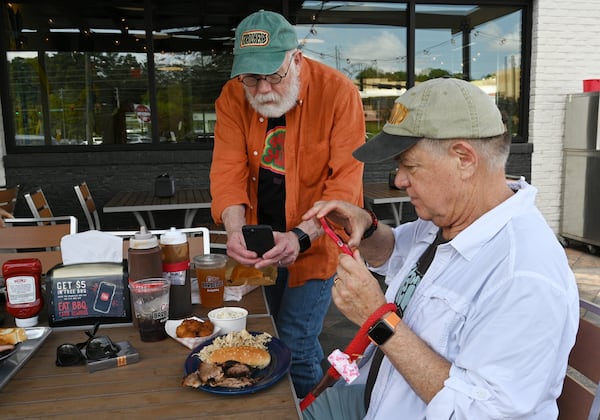 Roy Trimble (left) and Guy Tucker, photograph their barbecue plates at City Barbeque. Hyosub Shin / Hyosub.Shin@ajc.com)