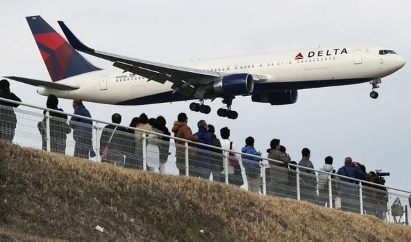 People watch as a Delta Air Lines jet lands at Narita Airport, about an hour east of central Tokyo. AP photo.