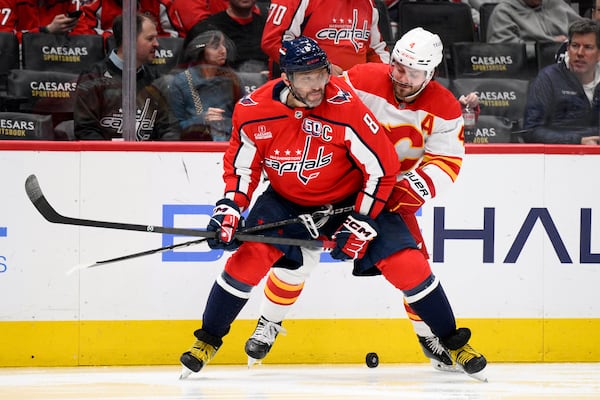 Washington Capitals left wing Alex Ovechkin (8) and Calgary Flames defenseman Rasmus Andersson (4) battle for the puck during the second period of an NHL hockey game, Tuesday, Feb. 25, 2025, in Washington. (AP Photo/Nick Wass)