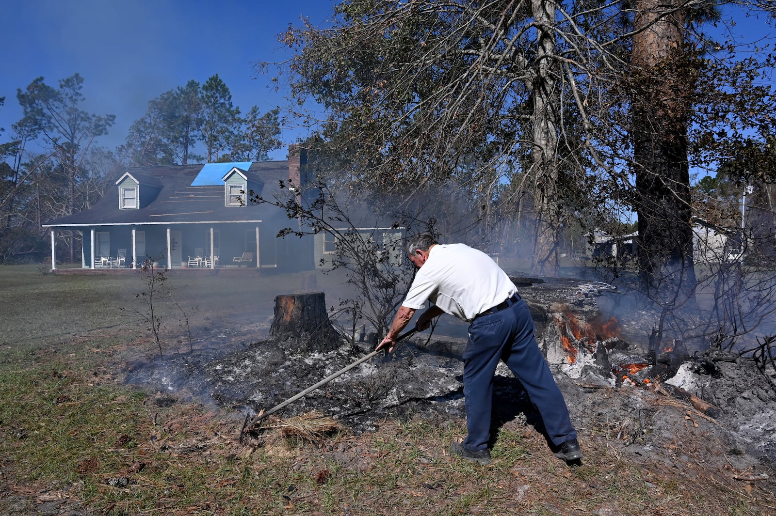 David Livingston burns piles of stumps and debris in the aftermath of Hurricane Helene in Hazlehurst, Ga. Livingston’s house had roof damages, some fallen trees and no power for 17 days. (Hyosub Shin/AJC)